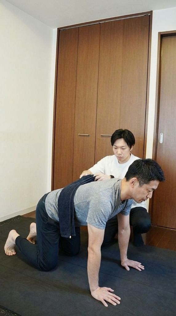 四つ這い姿勢を丁寧に指導するトレーナー